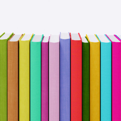 Een rij kleurrijke boeken naast elkaar op een witte achtergrond.